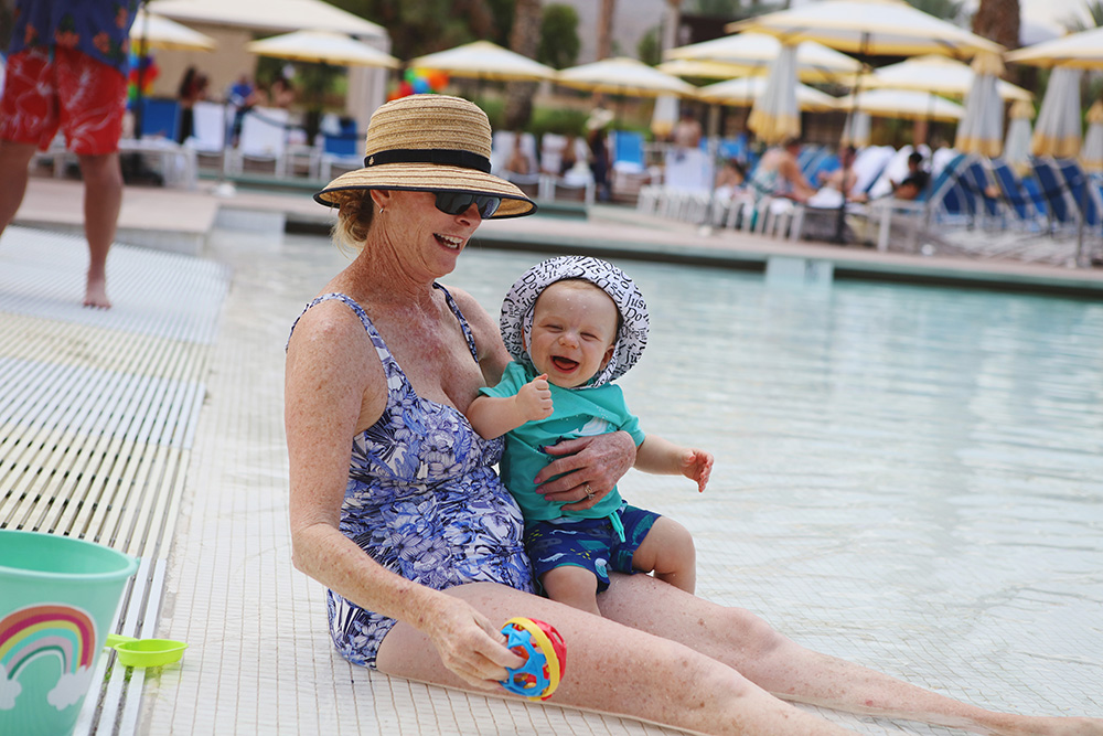 Candid moment with grandmother and grandchild sitting the beach area of a pool