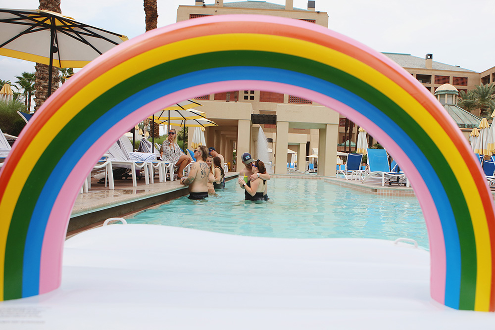 Cloud/rainbow pool float frames guest lounging in the pool