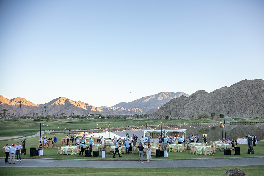 Wide angle view of a cocktail gathering on a golf course at sunset