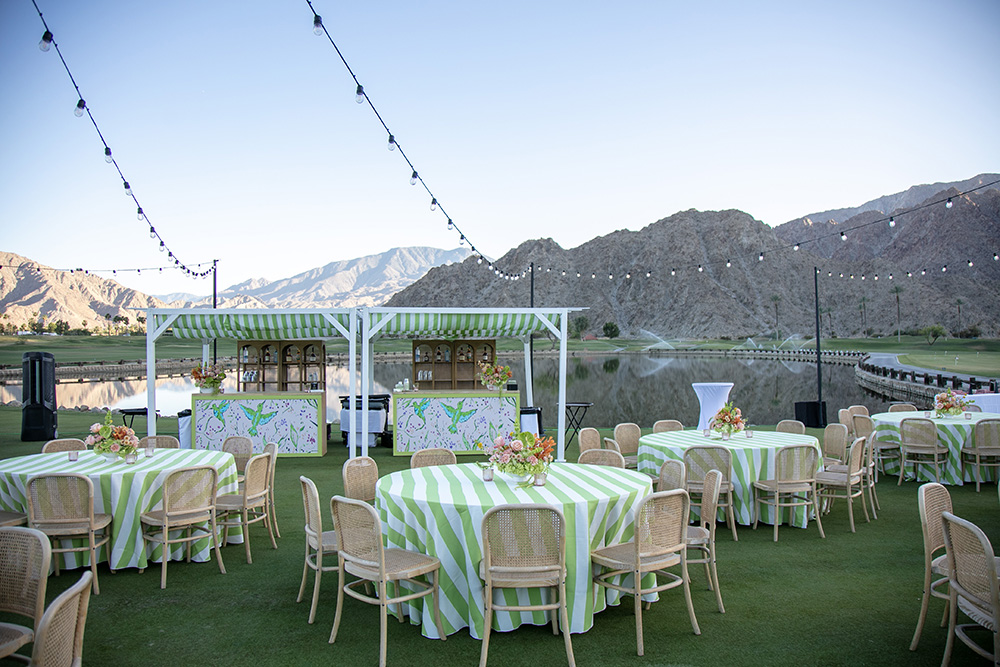 Photograph showing tables with flowers and a bar area for a cocktail party