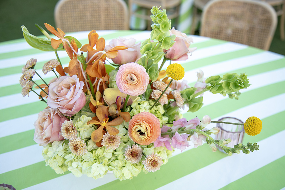 Closeup photograph of a floral centerpice on green and white striped table cloth
