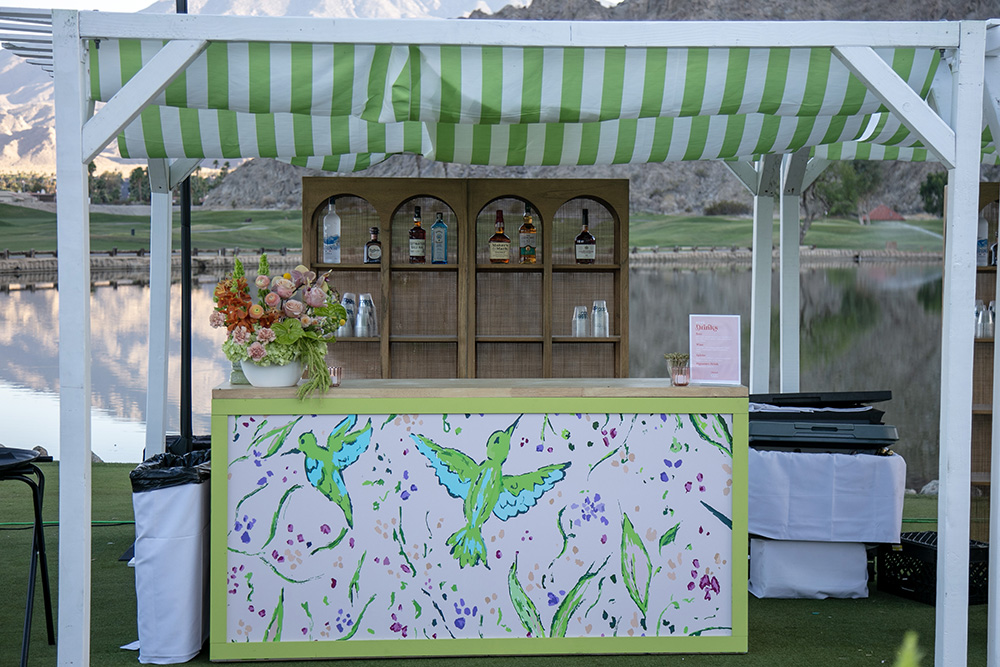 Detail photograph of a bar setup, in shades of vibrant green and white with flowers and humming bird painting