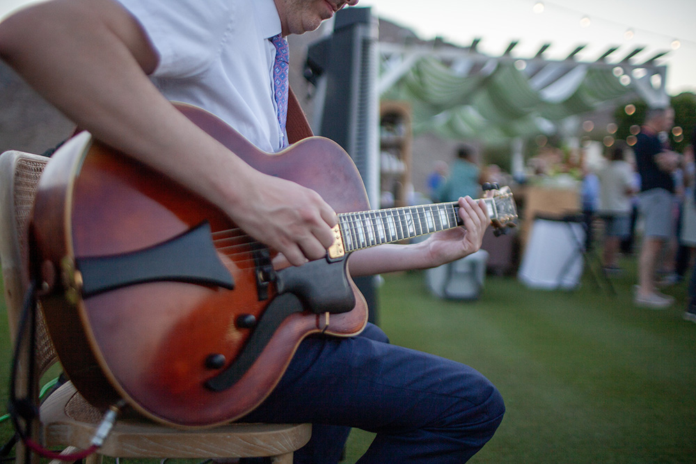 Photograph of a man playing guitar at a cocktail hour