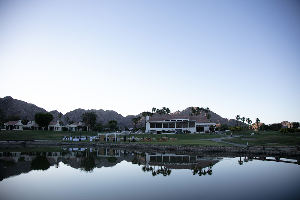 Wide photo of a cocktail party on the golf course with clubhouse in the background