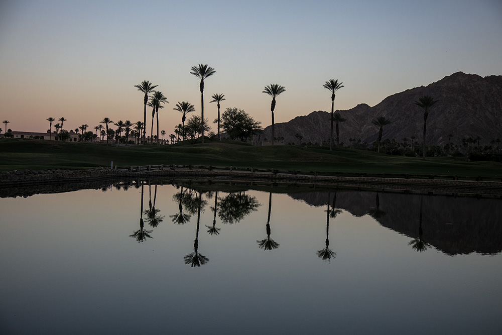 Dramatic reflection of mountains and palm trees in a man made lake at twilight