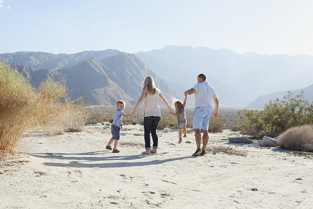Mother and father holding hand with their two toddlers in the desert