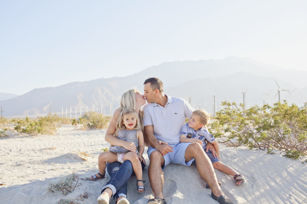 Family of four pose for a seated portrait at the wind turbines on Palm Springs