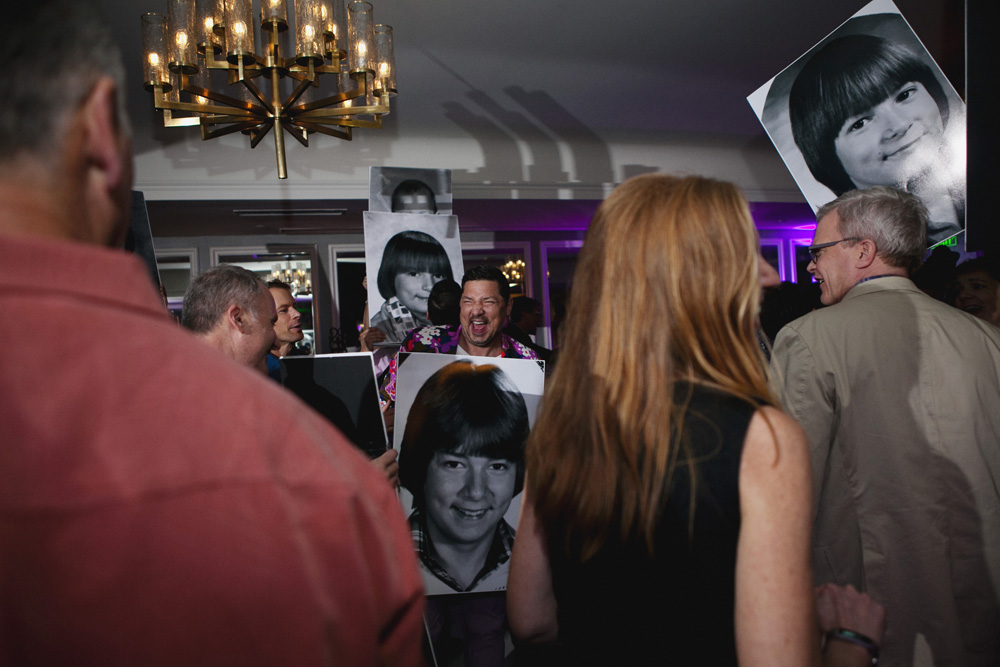 Man celebrating his 50th birthday poses with enlarged photos of himself as a child