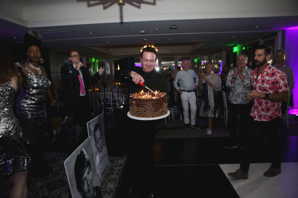 Party coordinator bring out a birthday cake onto the dance floor