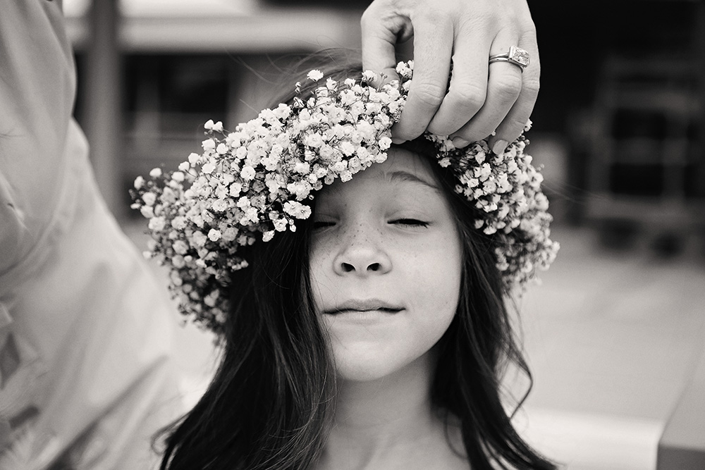 Black and white candid of someones hand adjusting a flower crown.