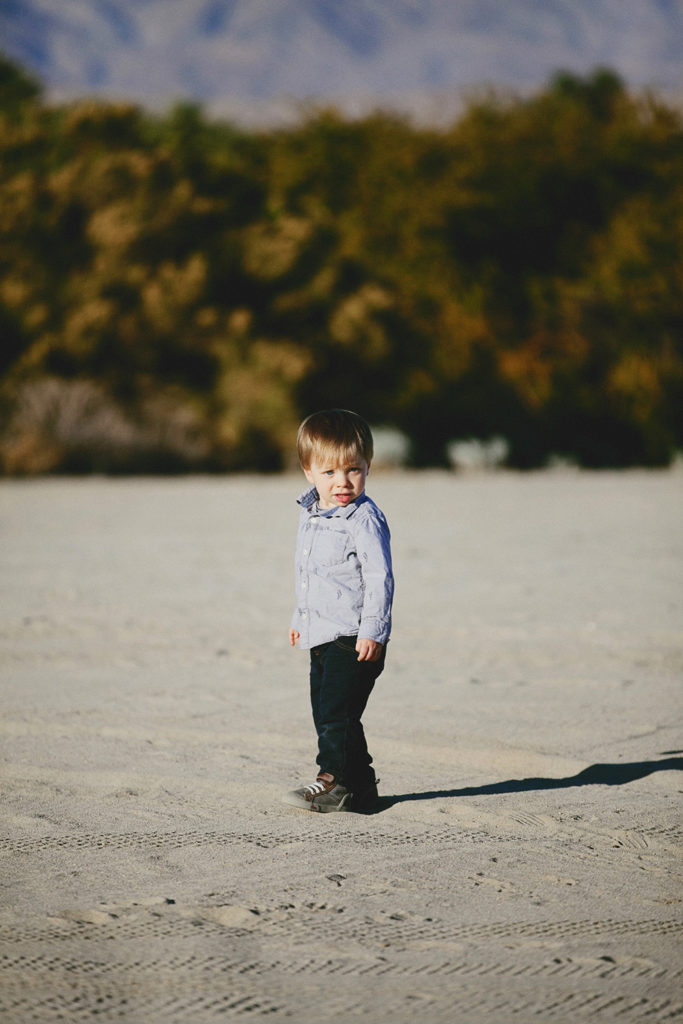A toddler stands in the desert at sunset