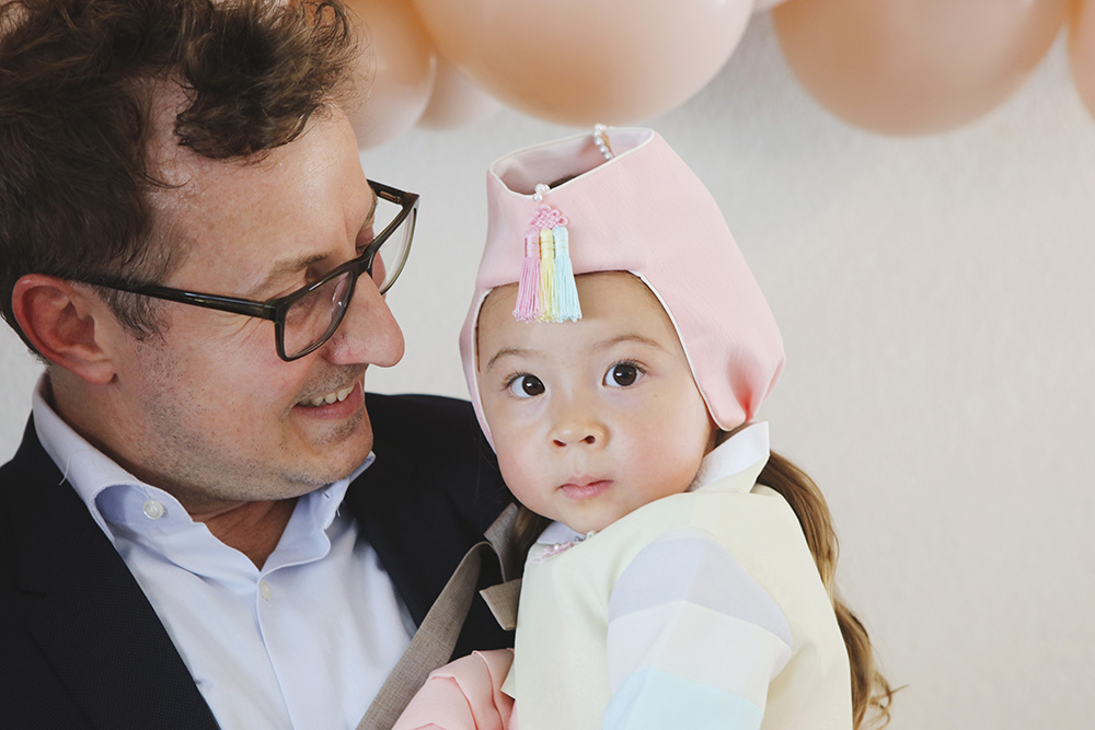 A father and his one year old daughter pose for a photo at her birthday party