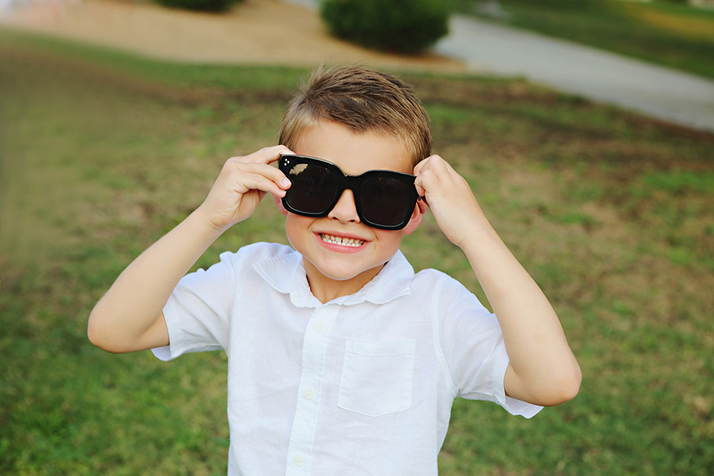 A young boy borrows his moms sunglasses for family photos
