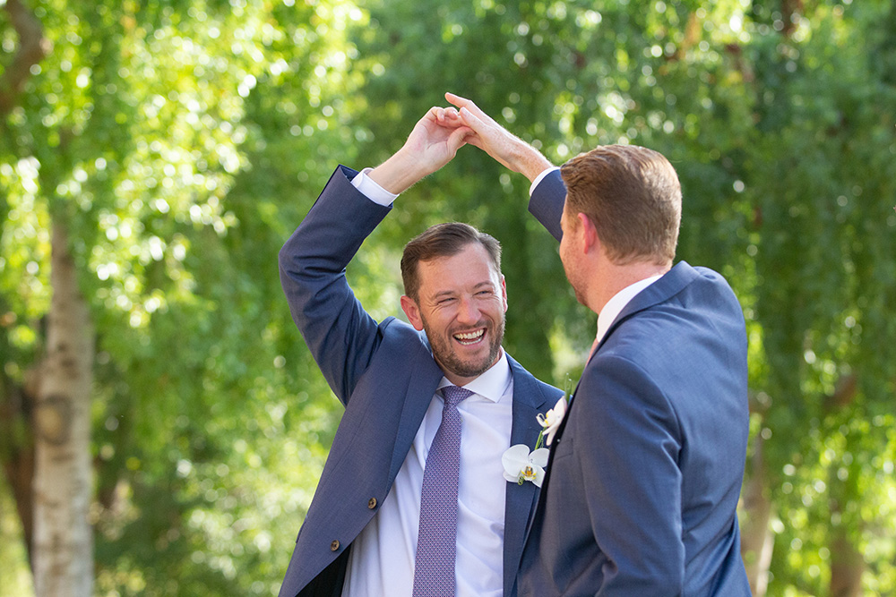 Two gentlemen wearing matching blue suits dance in the garden