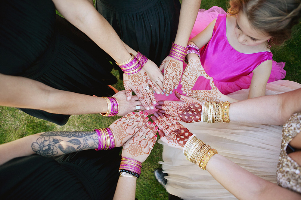 Bride and bridesmaids hold their hands together to show of mendhi painting