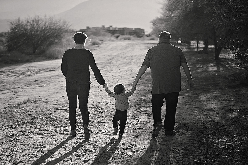 Mother and father walking away from the camera, holding their young sons hands between them
