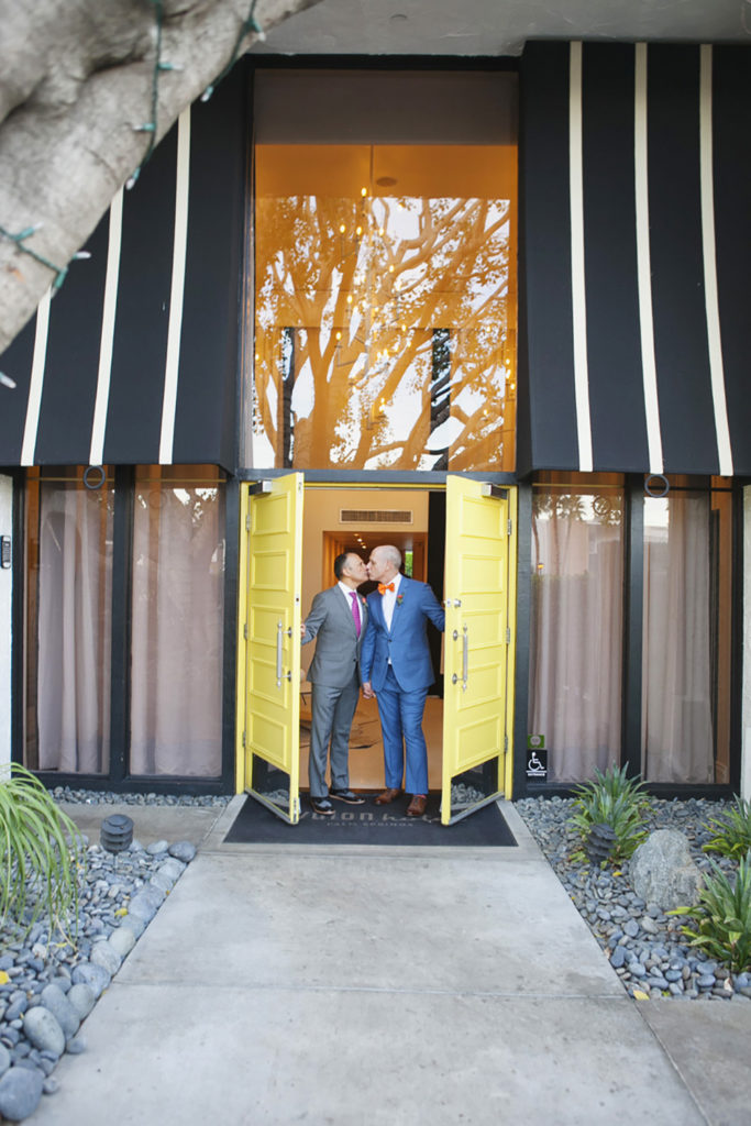Same sex couple kiss at iconic yellow palm springs doors