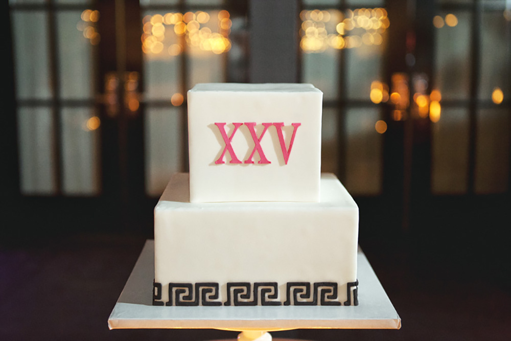 Square tiered wedding cake with the letters XXV on the top and black greek key around the bottom
